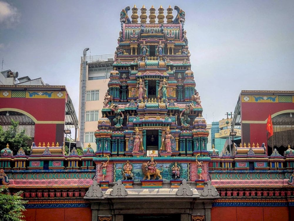 Multi-tiered Gopuram tower decorated with colorful, detailed Hindu deity sculptures